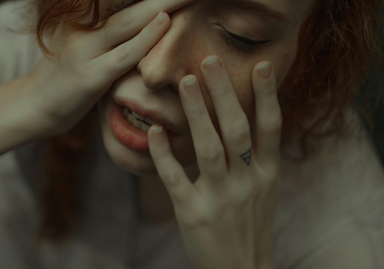 Primer plano de una mujer con las manos sobre el rostro y los ojos cerrados