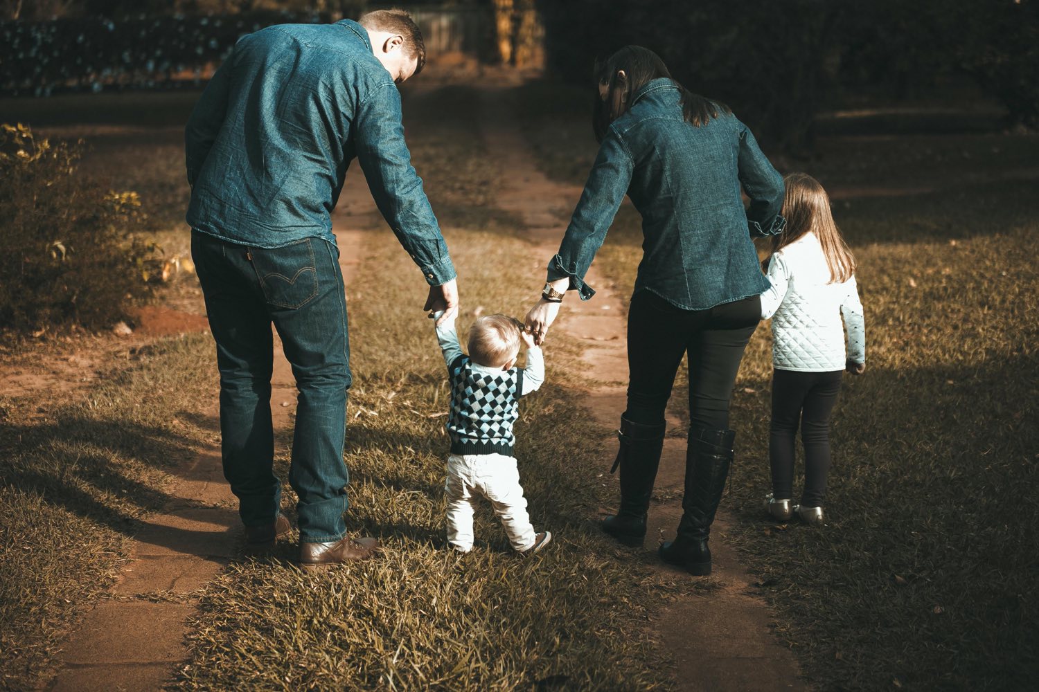 Una familia camina tomada de la mano por un sendero al atardecer