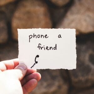 person holding piece of person holding piece of paper with phone a friend written text
